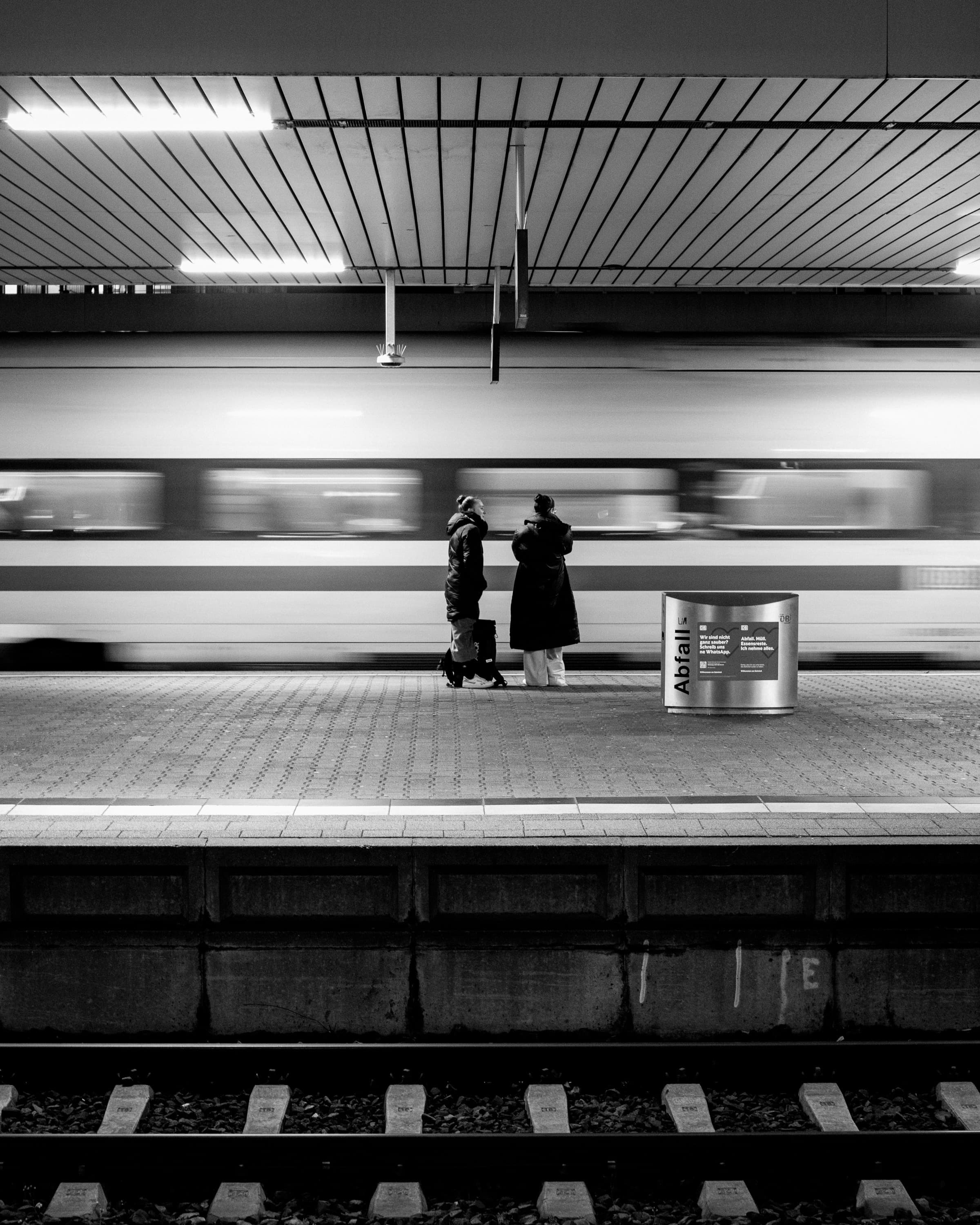 Two waiting figures in front of a passing train - briefly held.