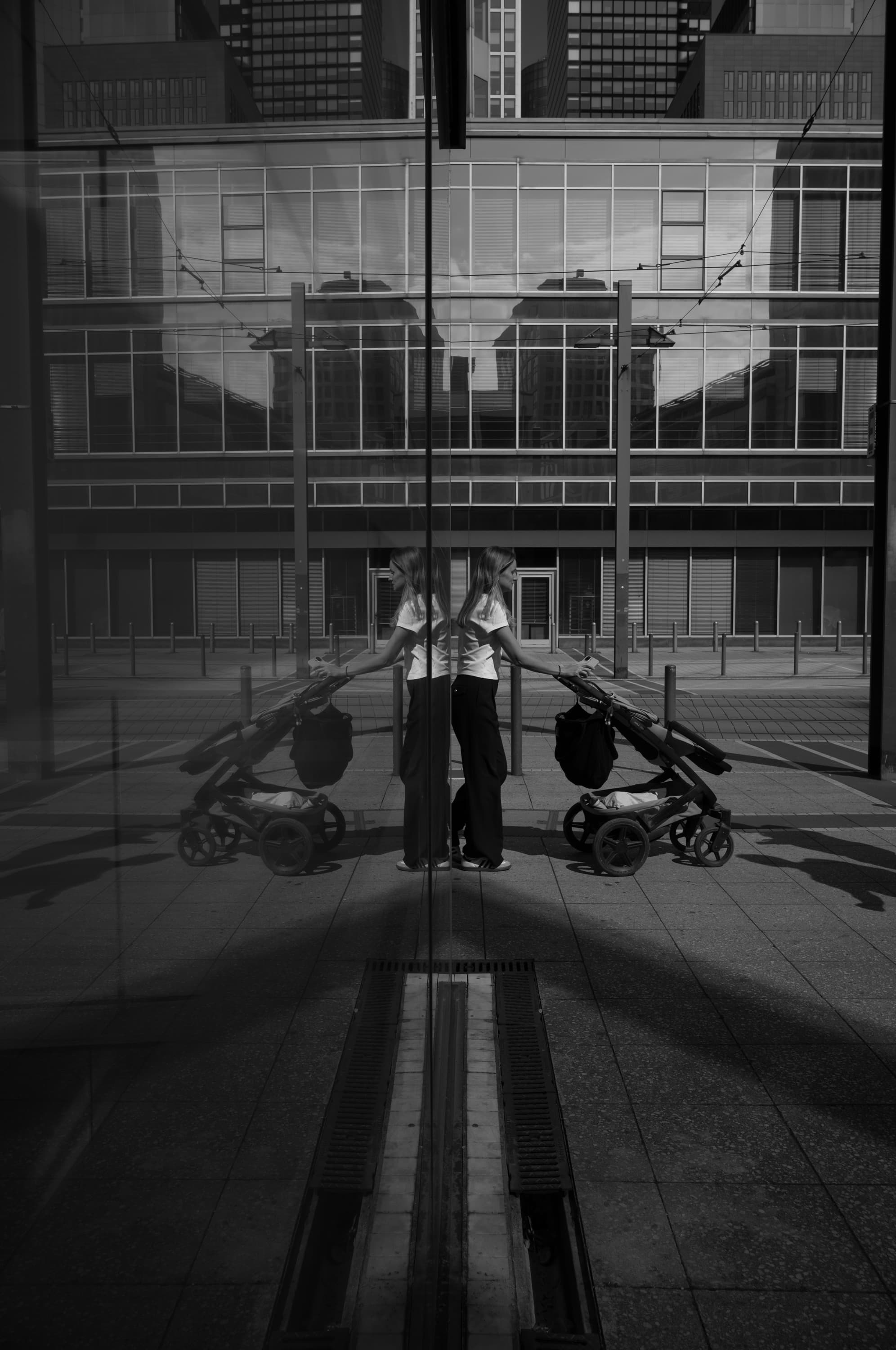 Woman with stroller between glass axes - held twice.