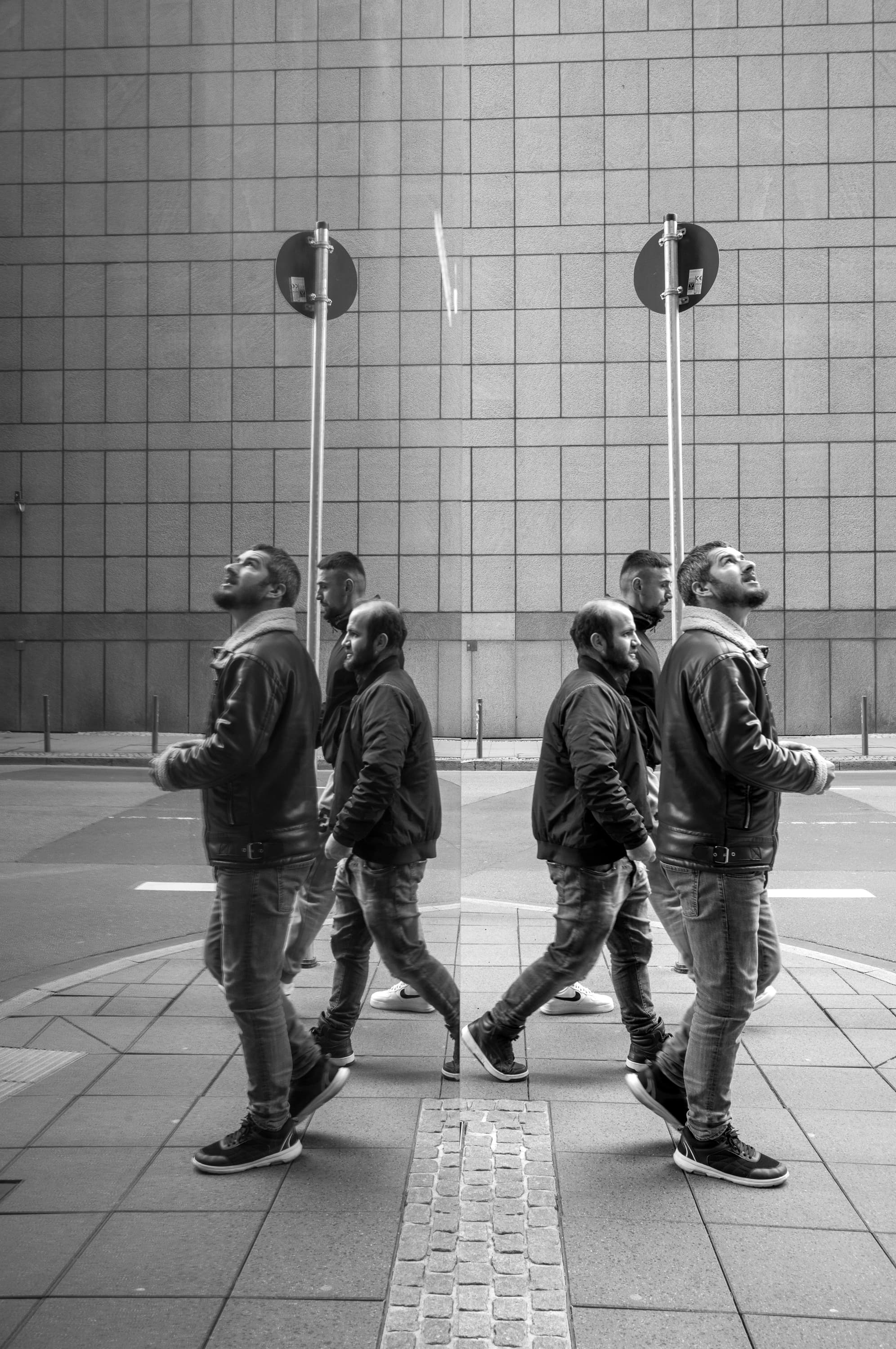 Passers-by and mirrored bodies before a grid facade - looking up.