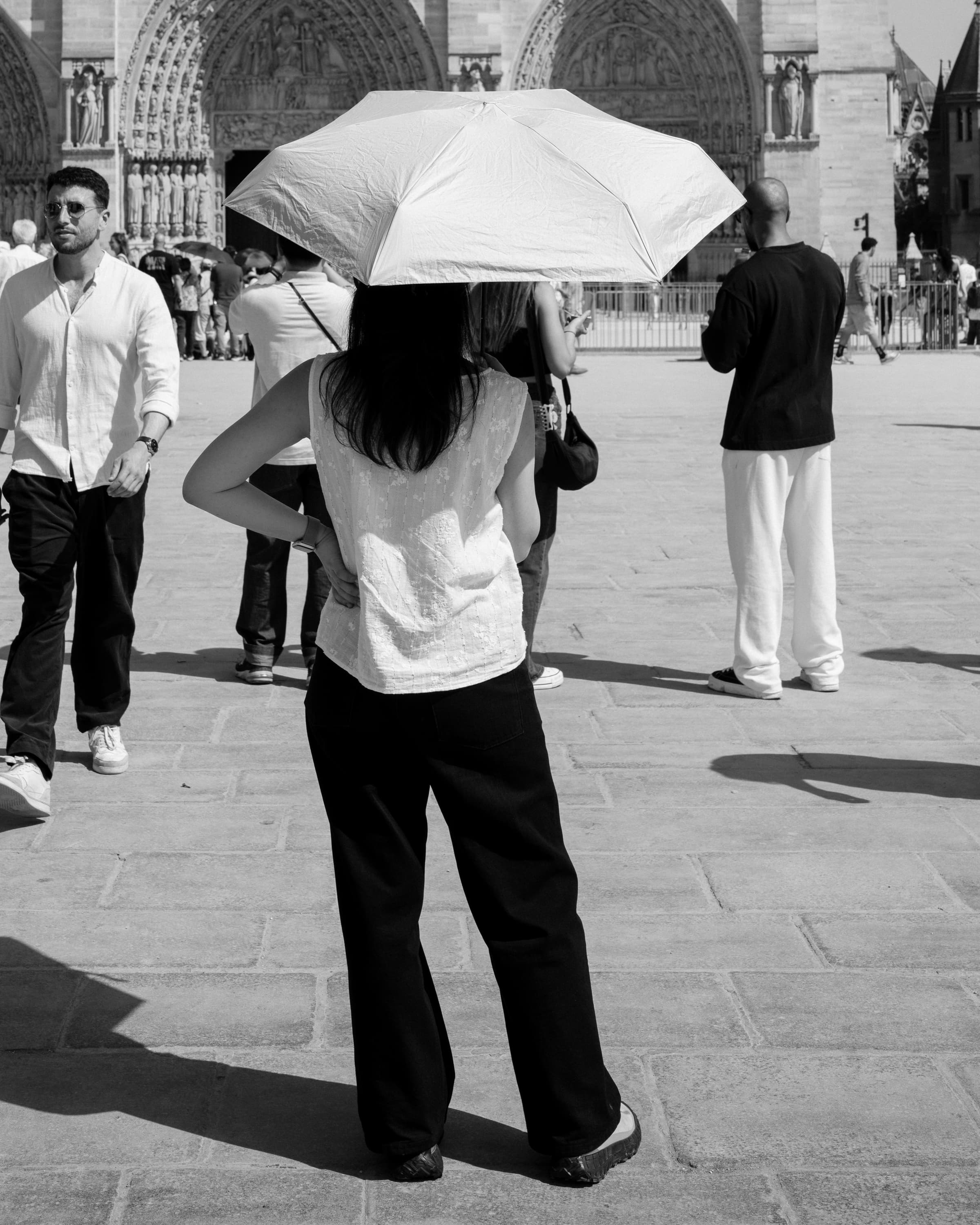 Figure from behind with a bright umbrella before Notre-Dame - on the square.